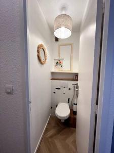 une salle de bains blanche pourvue de toilettes et d'une lumière. dans l'établissement BARCARESA-Appartement face mer et piscine wifi clim garage, au Barcarès