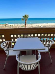 - une table et des chaises blanches sur un balcon donnant sur la plage dans l'établissement BARCARESA-Appartement face mer et piscine wifi clim garage, au Barcarès