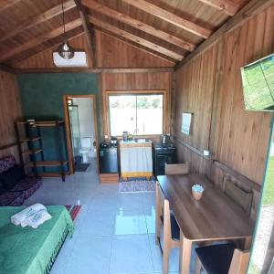 uma sala de estar com uma mesa e uma cozinha em Arandu Chalés em Imbituba