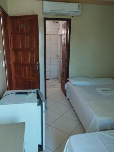two beds in a room with a door and a bathroom at Hotel Algaroba Anexo in Bom Jesus da Lapa
