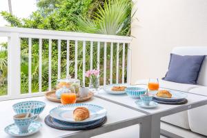- une table de petit-déjeuner avec des croissants et du jus d'orange sur une terrasse couverte dans l'établissement Art et mer suite Saint barth, à Anse des Cayes