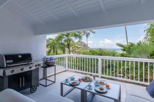 un balcón con una parrilla y una mesa con comida. en Art et mer suite Saint barth, en Anse des Cayes