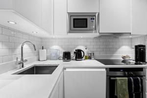 a white kitchen with a sink and a microwave at Londwell, Boutique Bliss Nestled in Knightsbridge by Harrods in London