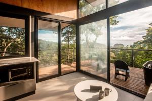 uma sala de estar com janelas grandes e uma mesa em Tiny Home Samambaia - Sea view and bathtub 