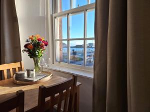 a table with a vase of flowers and a window at Ocean View in Campbeltown