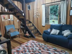 a living room with a blue couch and a staircase at Chalé Mauá Conforto e Arte in Visconde De Maua