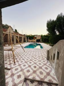 a pool with a tiled patio with a hammock next to it at West Bank luxury villa in Luxor