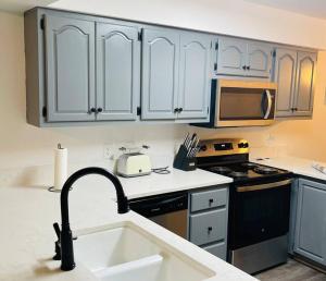 a kitchen with white cabinets and a kitchen sink at Cheerful 3 bedroom house with patio in Auburn