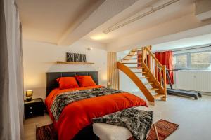 a bedroom with a red bed and a staircase at Cocon Relax - Jacuzzi - Cinéma in Montbéliard +47 photos