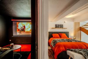 1 dormitorio con cama con almohadas de color naranja y mesa en Cocon Relax - Cinéma - Les Cocons de Nath, en Montbéliard