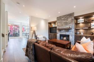 a living room with a leather couch and a fireplace at Englewoods Greens by Outpost Whistler in Whistler