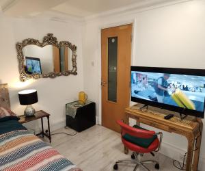 uma sala de estar com uma televisão e uma cadeira vermelha em Ensuit Room in Solihull Town Centre em Solihull