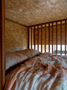 a bed in a room with a wooden wall at Hilltop Off Grid Tiny House with Outdoor Bath 