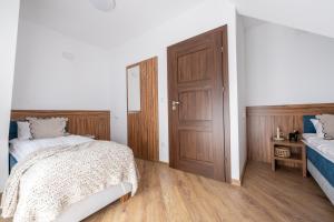 a bedroom with two beds and a wooden door at Para Apartments - Dwupoziomowe Apartamenty in Biały Dunajec