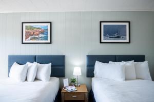 two beds in a hotel room with two pictures on the wall at Anchorage Motel in Bar Harbor