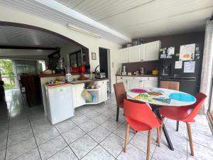 a kitchen with a table and red chairs in it at À 15’ de Poe Belle Villa in Bourail
