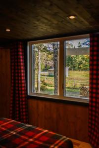 Schlafzimmer mit einem Fenster mit Blick auf ein Feld in der Unterkunft Ranch de Frisons le Fer à Cheval - Le Madison - Chalet Rustchic au pied du Mont Mégantic in La Patrie