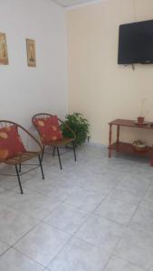 コリエンテスにあるApart Belgranoの椅子2脚、テーブル、テレビが備わる客室です。