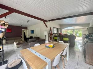 a dining room and living room with a wooden table at À 15’ de Poe Belle Villa in Bourail
