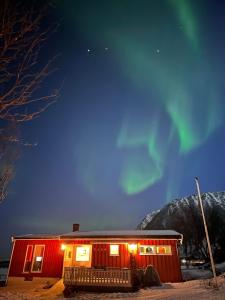 a red cabin with the aurora in the sky at Midnattsolveien 3158,Sommarhusstrand in Laukvik