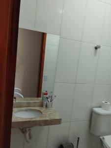 ein Bad mit einem Waschbecken und einem Spiegel in der Unterkunft LOCAMAR in Itanhaém