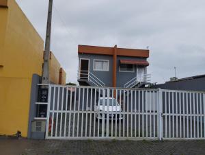 Ein weißer Zaun mit einem weißen Auto vor einem Haus. in der Unterkunft LOCAMAR in Itanhaém