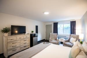 a bedroom with a large bed with a television and chairs at Anchorage Motel in Bar Harbor