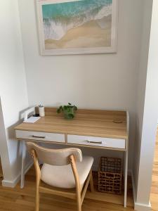 a desk with a chair next to a wall with a picture at Aura Apartment-LJHooker Yamba in Yamba