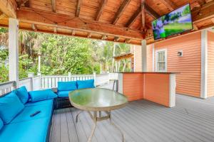 - une terrasse couverte avec un canapé bleu, une table et une télévision dans l'établissement Palm City Home with Decks and Florida Room - Near Golf, à Stuart