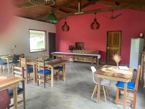 uma sala de jantar com mesas de madeira e uma parede rosa em Pousada Rancho da Serra PETAR em Iporanga