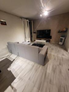 a living room with a couch and a television at Chambre neuve dans un appartement partagé à 10 minutes du circuit in Allonnes