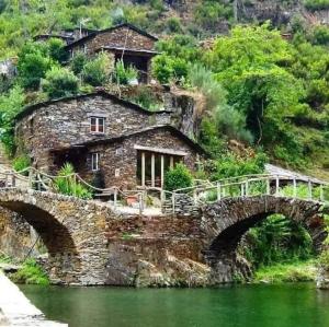 a stone house on a hill next to a bridge at CASA do AÇÔR in Aldeia das Dez