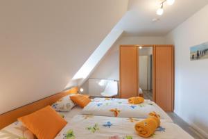 een slaapkamer met 2 bedden en oranje kussens bij Ferienhaus Frisia - Wohnung 2 in Nordstrand