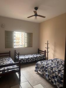 1 Schlafzimmer mit 2 Betten und einem Deckenventilator in der Unterkunft Apartamento na rua do Santuário in Aparecida