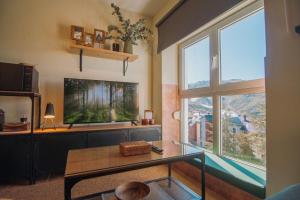 a living room with two large windows and a table at Alpine Home Sierra Nevada in Sierra Nevada