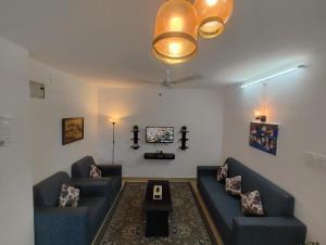 NK Homes - Serviced Apartments في حيدر أباد: غرفة معيشة مع كنبتين زرقاوين وطاولة
