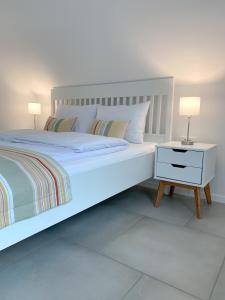 a white bedroom with a white bed and a nightstand at The View 22 in Cerklje na Gorenjskem