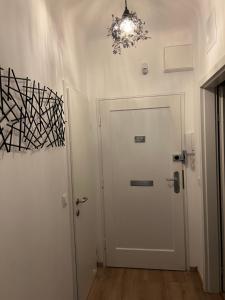 einen Flur mit einer weißen Tür und einem Kronleuchter in der Unterkunft Wohnung 1210 in Wien