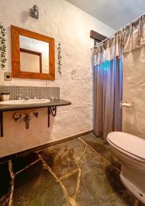 uma casa de banho com um WC, um lavatório e um espelho. em Sitio Del Serrans c lazer completo em Guararema SP em Guararema
