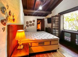 um quarto com uma cama e um candeeiro sobre uma mesa em Sitio Del Serrans c lazer completo em Guararema SP em Guararema