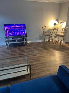 Indigo DowntownWalkable KingBed في رالي: غرفة معيشة مع تلفزيون وطاولة وكراسي