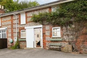 una vecchia casa di mattoni con una porta bianca di The Stable—Historic Property in Downwood Vineyard a Blandford Forum