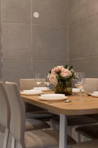 a wooden table with glasses and a vase of flowers at Luxurious & Spacious Central Residence with Balcony in Budapest