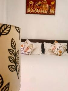 ein Bett mit weißen Kissen und einem Bild an der Wand in der Unterkunft River Side Guest house in Maskeliya