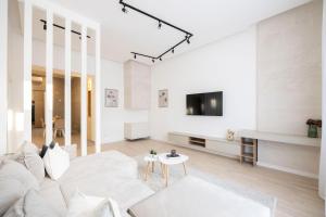 a living room with a white couch and a tv at Luxurious & Spacious Central Residence with Balcony in Budapest
