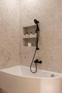 a bath tub with a shower head in a bathroom at Luxurious & Spacious Central Residence with Balcony in Budapest