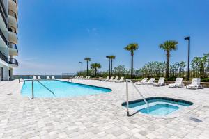 a swimming pool with chairs and palm trees and the ocean at Grand Pointe Unit 303 in Orange Beach