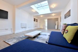a living room with a blue couch and a skylight at Fabulous duplex apartment in Dalston Junction in London