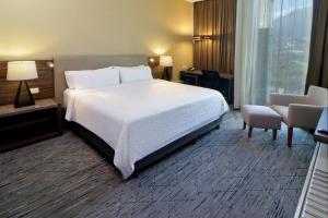 - une chambre avec un grand lit blanc et une chaise dans l'établissement Holiday Inn Express & Suites Monterrey Valle, an IHG Hotel, à Monterrey