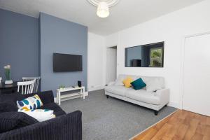 Derby central 4 bed house - Free parking في ديربي: غرفة معيشة مع أريكة وتلفزيون